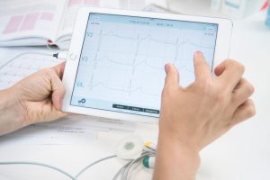 A cardiologist zooming on iPad the ECG and Cardiosecur Pro device on his desk